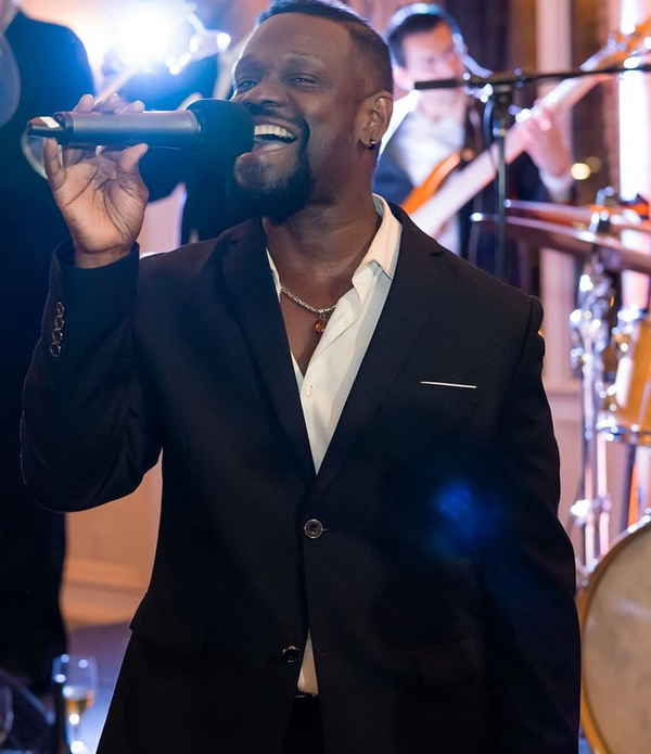 Professional picture of our male New Jersey singer for events passionately singing and looking to camera during performance | Altus Entertainment